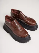 Mocasines color marrón con estampado de cocodrilo y plataforma negra con suela dentada.