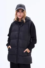 Chaleco puffer largo de color negro, con cierre frontal completo, capucha ajustable con cordones y bolsillos laterales. Diseño acolchado con costuras horizontales.