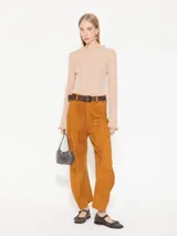 Top color beige de tejido de punto acanalado, con cuello redondo y mangas largas con volados en los puños.