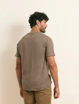 Remera básica de algodón color beige, de manga corta, con cuello redondo y un pequeño detalle bordado en el pecho.