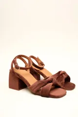 Sandalia de tacón cuadrado medio, confeccionada en terciopelo negro. Presenta un diseño de tiras cruzadas con nudo en la parte delantera y una tira ajustable con hebilla en el tobillo.