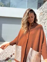 Saco tejido de punto en color marrón chocolate, con corte holgado y mangas anchas. Presenta cierre frontal con botones y dos bolsillos delanteros grandes en material metalizado color champán.