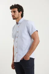 Camisa de manga corta a rayas verticales blancas y celestes, con cuello abotonado y bolsillo en el pecho.