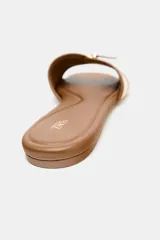 Sandalia plana con base color marrón y tiras cruzadas de tela color crema con hebilla dorada.