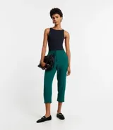 Pantalón de vestir femenino color marrón oscuro, de corte fluido y tiro medio/alto, con cintura elástica ajustable mediante cordón. Presenta bolsillos laterales y cierre frontal.