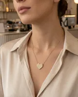 Collar de acero con baño de oro, compuesto por una cadena fina y un dije en forma de corazón pavé con incrustaciones de circonias.
