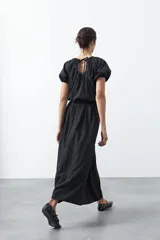 Falda larga plisada color marrón, de silueta amplia y caída fluida.