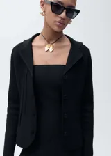 Chaqueta de punto negra con cuello de solapa, cierre frontal de botones y diseño entallado de manga larga.