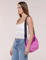 Cartera bandolera de lona naranja en forma de medialuna, con correa ajustable negra y cierre principal.