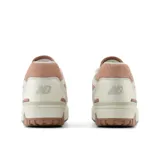 Championes New Balance 550 de cuero color crema con detalles en rosa y suela marrón.