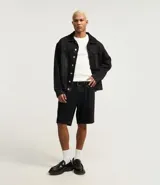 Bermuda de jeans de algodón, color negro, corte slim fit, con cintura fija, trabilla, cierre tradicional y bolsillos delanteros y traseros.