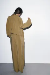 Pantalón tipo palazzo de corte recto y tejido fluido, color naranja. Presenta cintura elástica con cordón ajustable y bolsillos laterales.