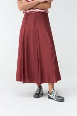 Falda larga beige de corte evasé, con diseño fluido y detalles de costuras verticales en la parte delantera.