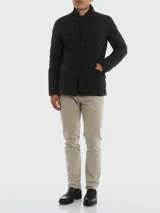 Chaqueta de vestir negra acolchada con relleno de plumas y cuello mao. Presenta cierre frontal con botones, un bolsillo en el pecho y dos bolsillos laterales con solapa. Fabricada en tejido Gortex.