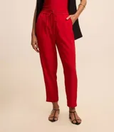 Pantalón de vestir femenino color marrón oscuro, de corte fluido y tiro medio/alto, con cintura elástica ajustable mediante cordón. Presenta bolsillos laterales y cierre frontal.