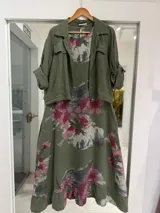 Vestido midi verde militar con estampado floral en tonos rosados y grises, de corte acampanado y tirantes finos.