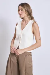 Chaleco de punto color crema con escote en V y cierre frontal con botones a tono.