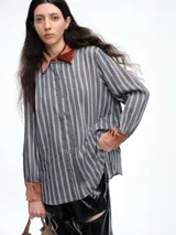 Camisa de corte relajado con estampado de rayas verticales, destacada por detalles en terciopelo en el cuello, puños y canesú. Presenta cierre frontal con botones y mangas largas.