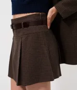 Short pollera de corte sastrero con estampado a cuadros, diseño con pliegues frontales, cintura estructurada con pasadores y cinturón incluido.