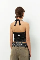 Top negro de satén con cuello halter y espalda descubierta.