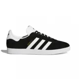 Championes adidas modelo Gazelle, confeccionados en gamuza negra con las icónicas tres tiras laterales y refuerzo en el talón en color blanco. Presenta suela de goma blanca y el nombre del modelo en letras doradas en el lateral.