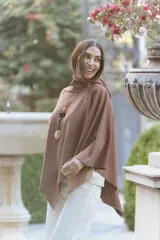 Poncho de textura suave tipo polar, color marrón, con cuello alto y diseño amplio de corte asimétrico.