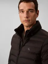 Campera puffer de peso medio Calvin Klein, color negro, con diseño acolchado, cuello alto y cierre frontal de cremallera. Presenta el logo de la marca estampado en el pecho.