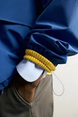 Cazadora técnica relaxed fit de color azul, con cuello subido, capucha ajustable, bolsillos frontales de plastrón con solapa, cierre de cremallera oculta y puños elásticos.