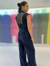 Mono largo azul marino con estampado dorado en la parte superior, cuello mao, sin mangas, con cinturón y bolsillos laterales.