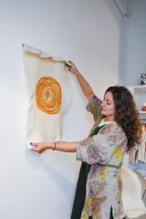 Tapiz de lana merino afieltrada a mano, color crema con espiral color mostaza.