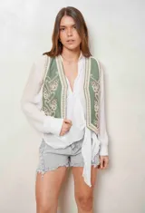 Chaleco de denim color camel con bordados florales en blanco y aplicaciones de perlas en el frente.