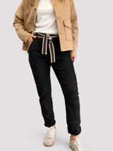 Pantalón negro de corte relajado con textura arrugada, cintura elastizada y lazo ajustable a rayas. Cuenta con bolsillos laterales y diseño de estilo urbano.