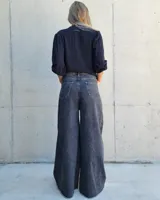 Pantalón de jean color beige, de corte recto y tiro alto, con ruedo deshilachado y cierre frontal con botón y cremallera.