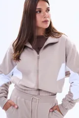 Campera de felpa con cierre frontal, cuello alto y diseño color block en negro y blanco en las mangas. Presenta un corte holgado y puños elásticos.