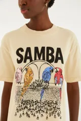 Remera beige de algodón con diseño estampado frontal que incluye la palabra "Samba" y cuatro loros de colores.