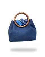 Bolso de mano tejido en color azul, con estructura rígida y asas circulares de madera. Presenta un aplique decorativo de piedras azules en la parte superior y cuenta con una cadena metálica desmontable para llevar al hombro.