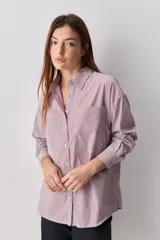Camisa de calce relajado con diseño a rayas verticales en tonos azul y blanco, cuello clásico, mangas largas con puños abotonados y cierre frontal con botones. Presenta bolsillos aplicados en el delantero y una silueta versátil.