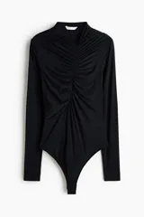 Body de manga larga color negro, confeccionado en punto elástico con escote en V y diseño drapeado en el frente mediante costuras fruncidas. Presenta cierre con botones a presión en la entrepierna y parte inferior tipo colaless.