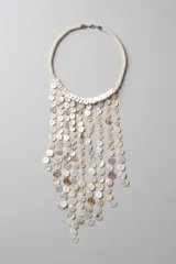 Collar tipo pechera confeccionado con múltiples tiras de discos de nácar en tonos blancos y marfil, unidas a una estructura corta de cuentas tubulares.