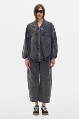 Jean de pierna ancha que se estrecha hacia el tobillo, con cintura ajustada y corte relajado en cadera y muslo. Color gris oscuro con efecto acid wash, tiro medio y costuras en hilo dorado.