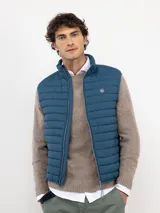Chaleco acolchado de nylon, color azul, con cierre frontal de cremallera, cuello alto y logo engomado en el pecho.