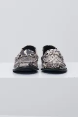 Mocasín negro de cuero con textura tipo cocodrilo, detalle de estribo metálico plateado en el empeine y costuras reforzadas en la puntera.