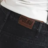 Pantalón de jean estilo baggy con corte barrel, color negro, con bolsillos laterales y logo bordado tono sobre tono.