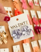 Par de aros tipo caravana con forma de flor color plateado.