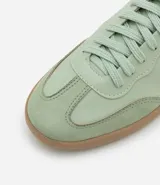 Championes de estilo retro tipo chutera, confeccionados en poliuretano color marrón con detalles en beige en los laterales y el talón. Presentan suela plana de goma color caramelo y cierre mediante cordones.