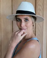 Sombrero de playa de paja color blanco con cinta negra alrededor de la copa.