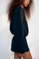 Falda pantalón de tiro bajo color azul marino, con detalle de falsos botones metálicos en el frente y cierre lateral con cremallera oculta.