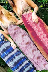 Vestido largo con escote en V, estampado en tonos rojizos y rosados, con un patrón ondulado. Presenta cut-outs laterales bajo el busto y breteles finos que se cruzan en la espalda.