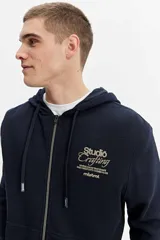 Campera con capucha y cierre frontal, confeccionada en tejido de algodón texturado color azul marino. Cuenta con bolsillos delanteros y detalle estampado en el pecho.