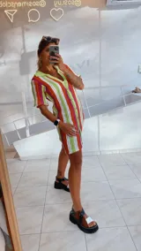 Vestido corto tejido calado a rayas horizontales en tonos naranja, amarillo y blanco, con cuello tipo polo y cierre frontal con botones.